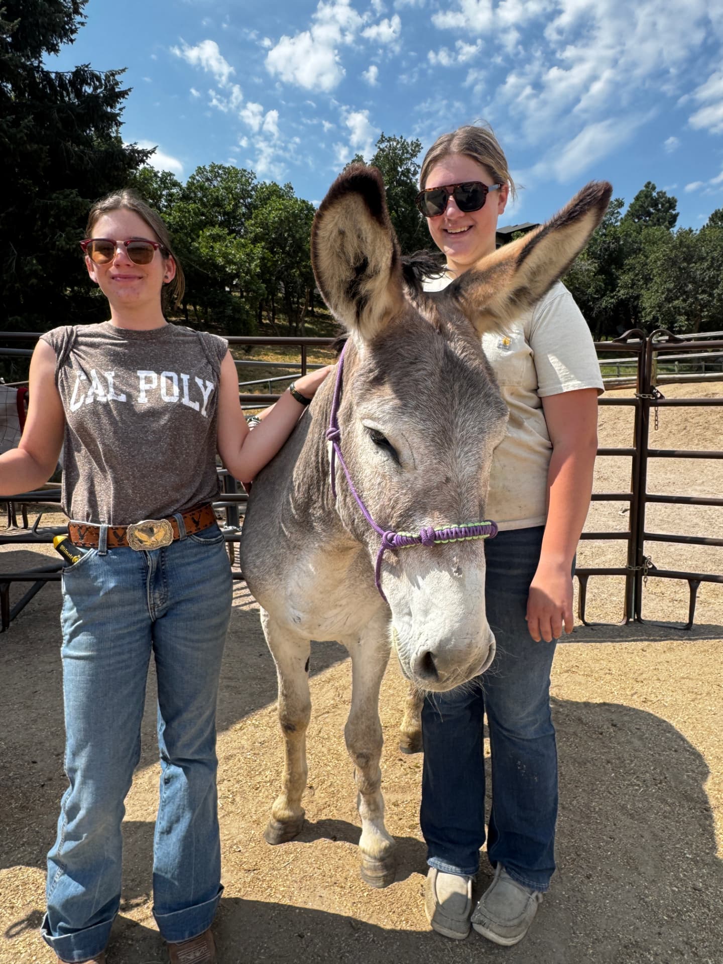 Two young women standing with a haltered burro in the round pen