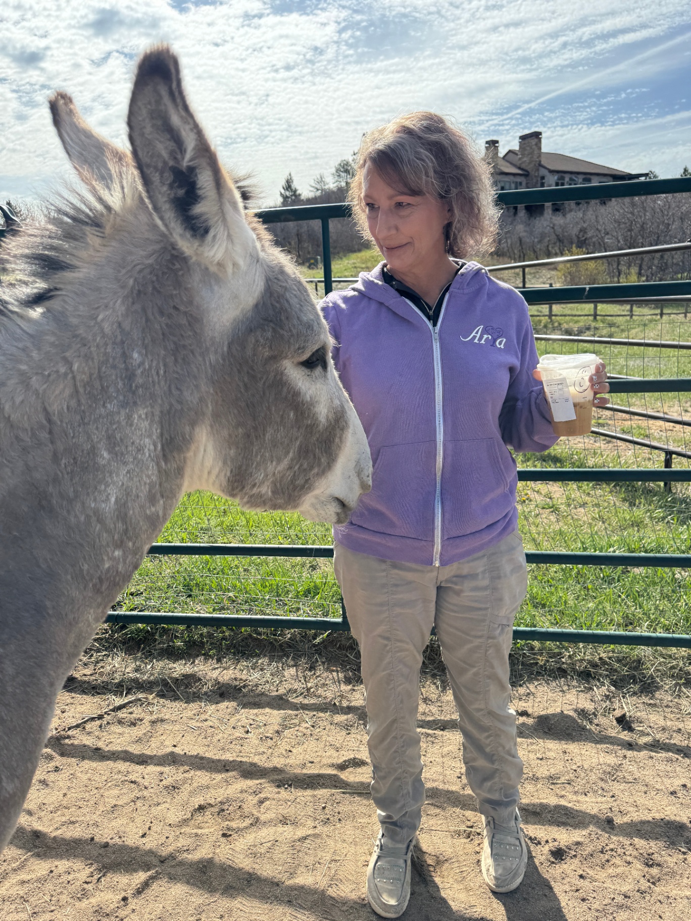 Stacy standing quietly with a grey burro at the fence