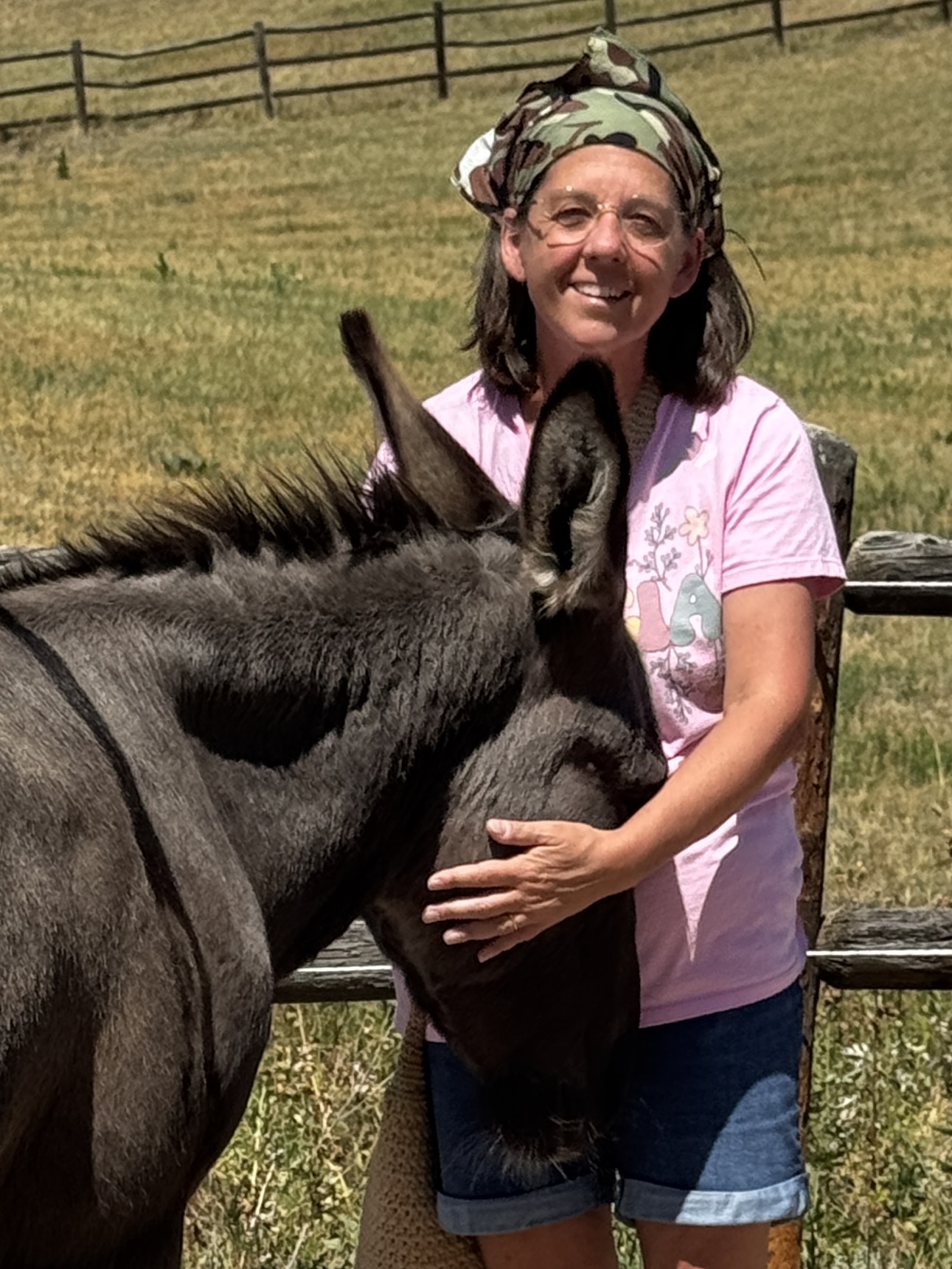 Aunt Stacy holding a burro's head close in the pasture