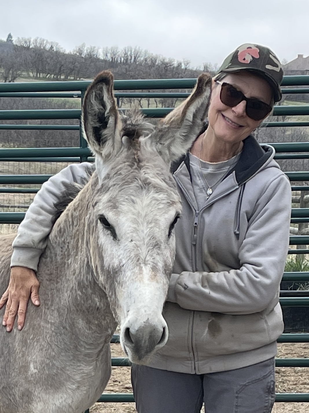 Stacy leaning against a gentled burro in the corral